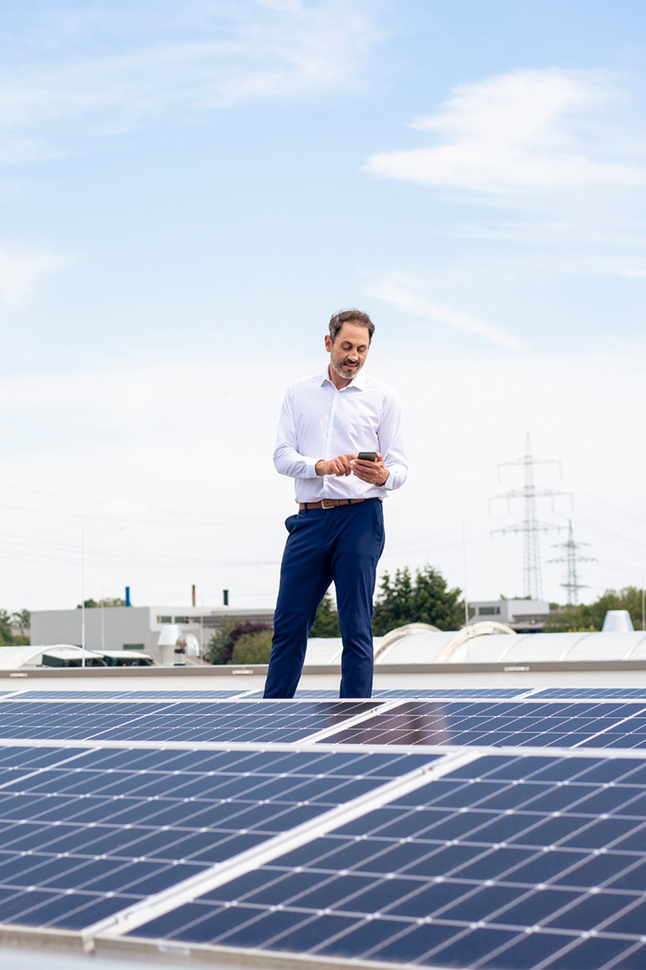 Ein Mann steht auf einem Dach auf dem eine PV Anlage installiert ist.