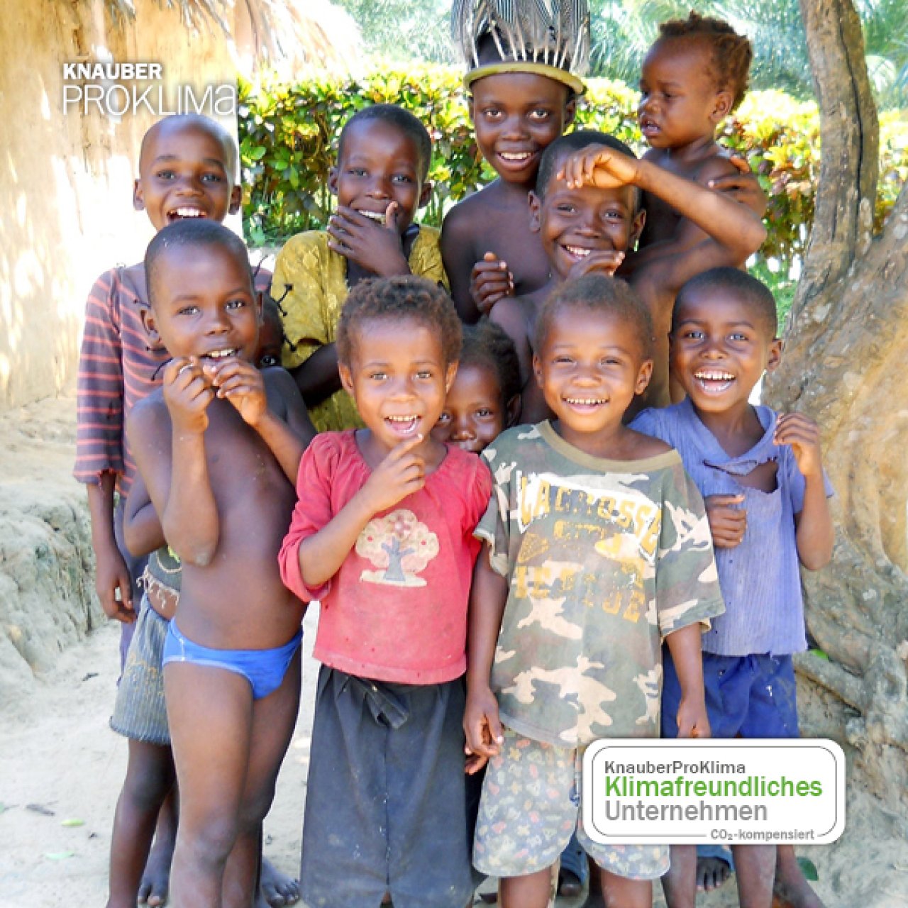 Gruppe lächelnder afrikanischer Kinder, einige in bunter Kleidung, vor grünem Hintergrund.