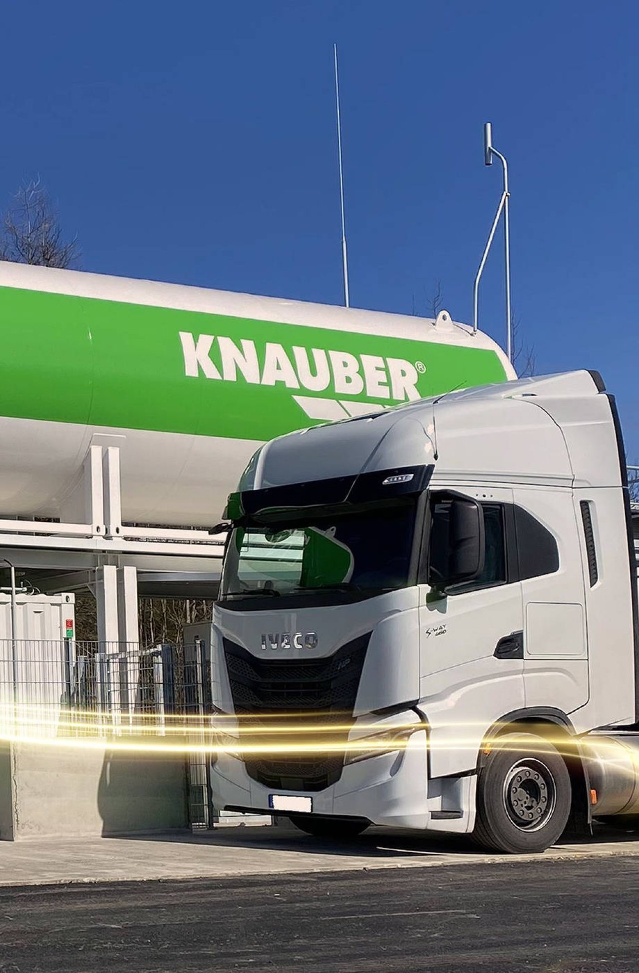 Ein weißer LKW steht vor einem weißen Tank mit dem Logo der Firma Knauber.