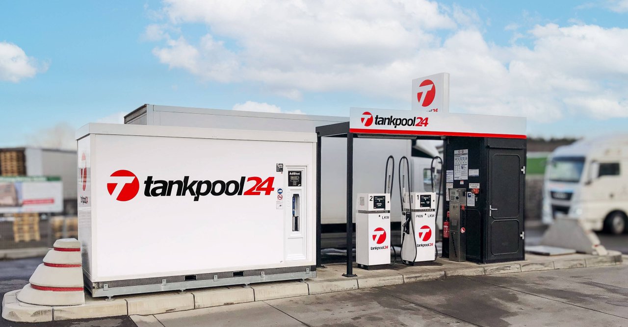 Tankstelle von tankpool24 mit zwei Zapfsäulen und einem weißen Container unter blauem Himmel.