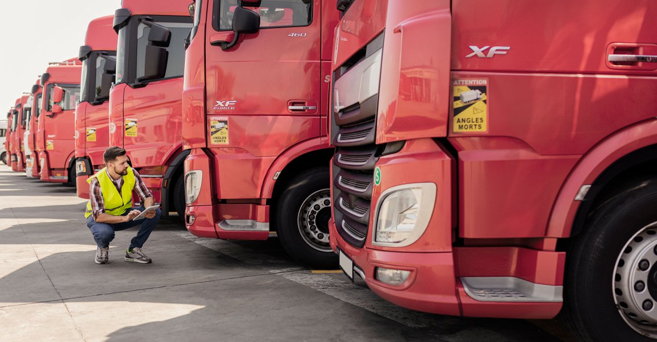 Ein Mann in Warnweste kniet vor roten LKW.