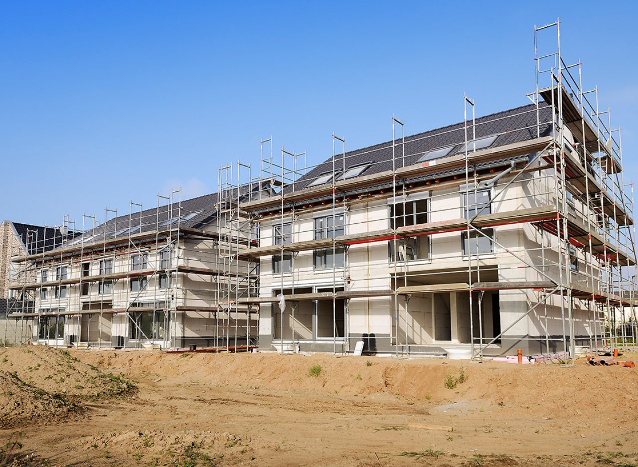 Ein Mehrfamilienhaus mit einem Baugerüst auf einer Baustelle.
