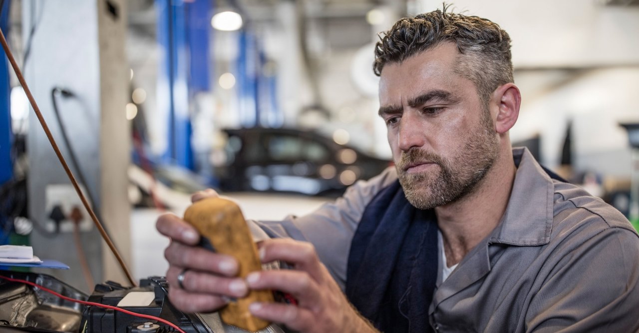 Ein Mann bedient in einer Werkstatt eine Maschine.