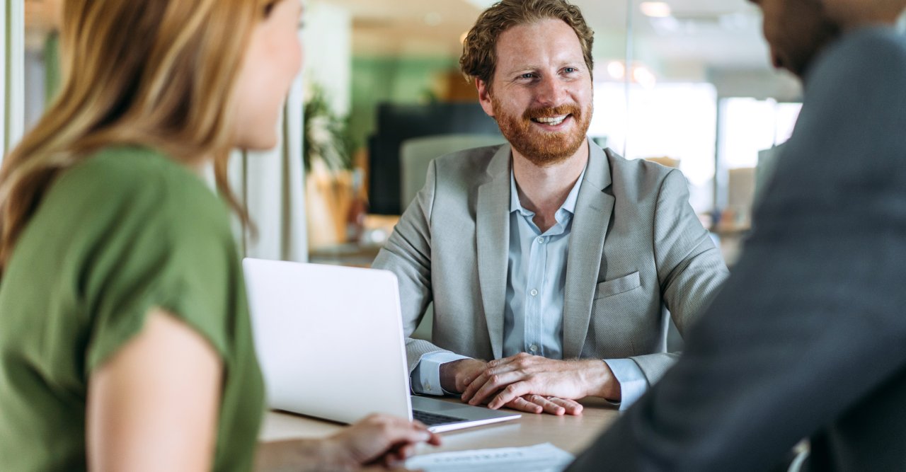 Ein Paar wird von einem bärtigen Mann beraten.