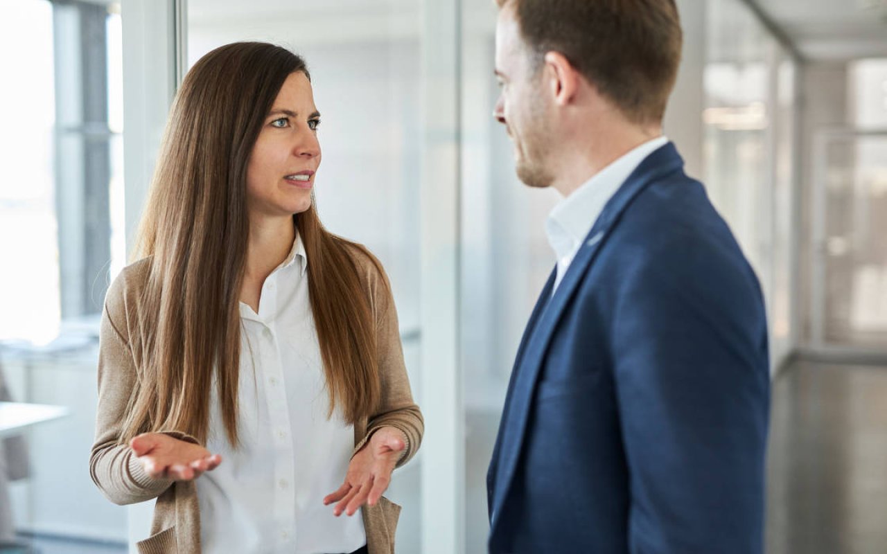 Zwei Kollegen im Businessoutfit sprechen miteinander.