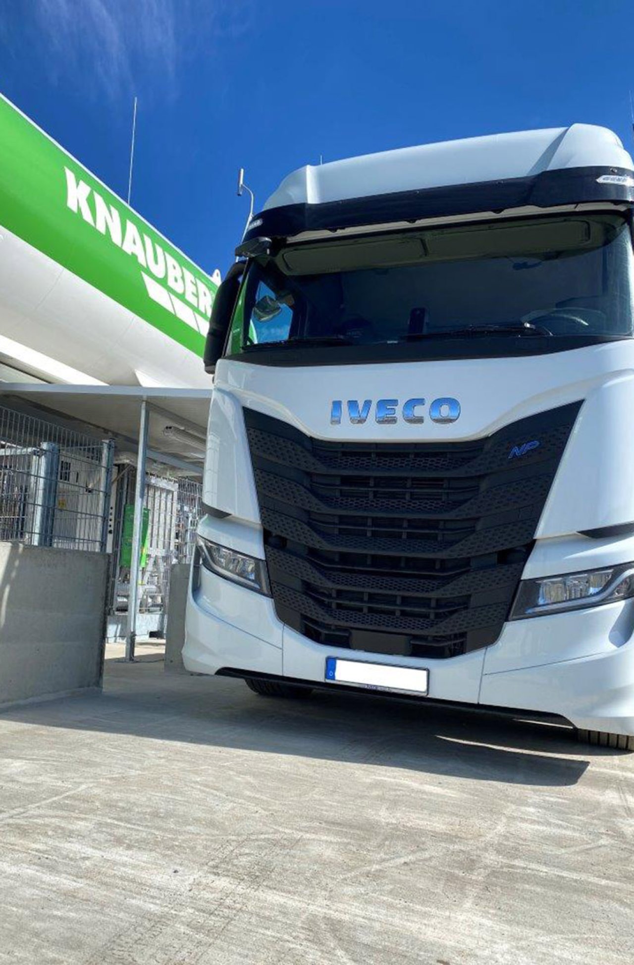 Ein weißer Iveco LKW steht vor einem weißen Gastank.