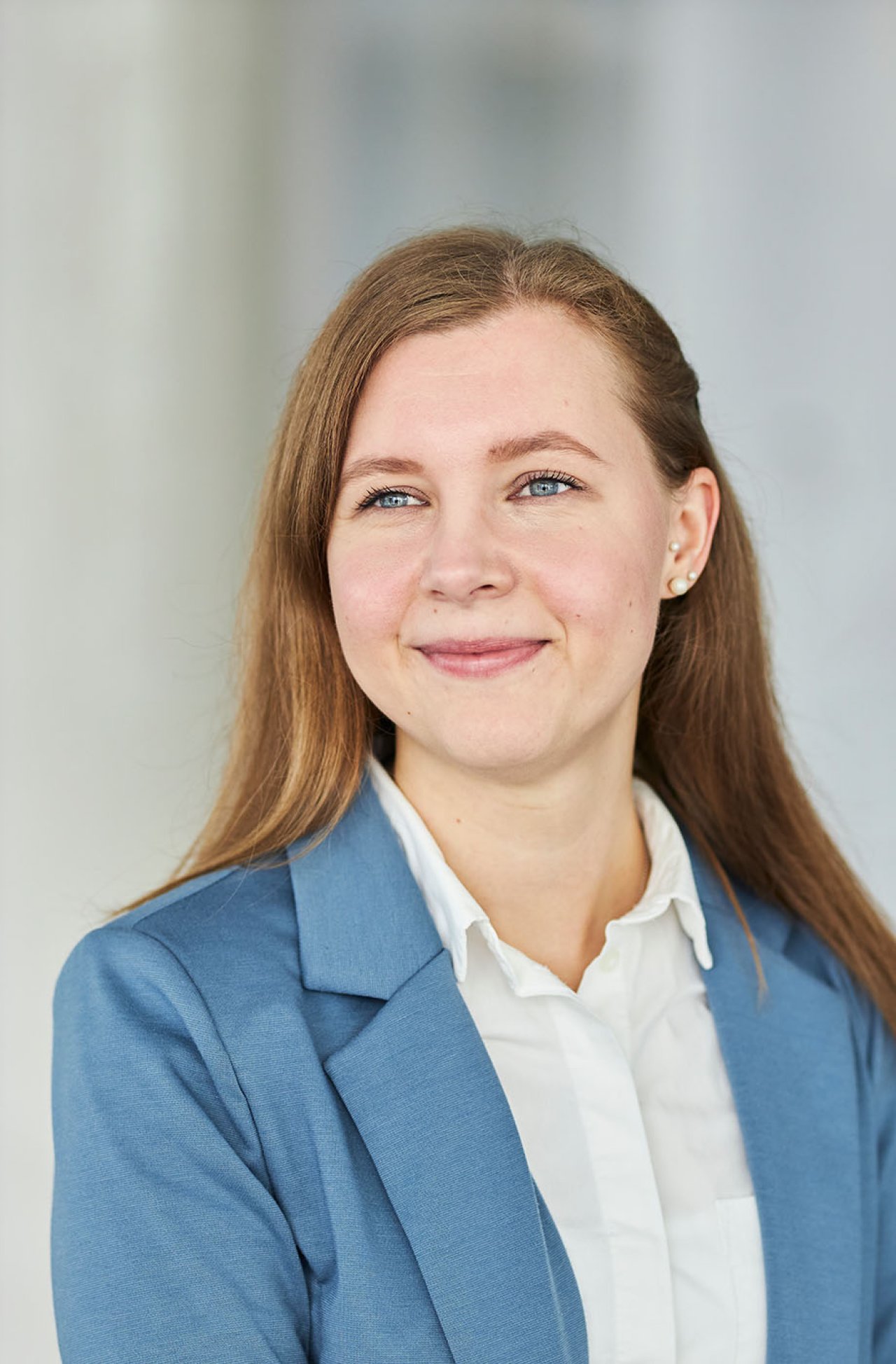 Eine junge Frau mit rotblonden Haaren und Jacket schaut lächelnd an der Kamera vorbei.
