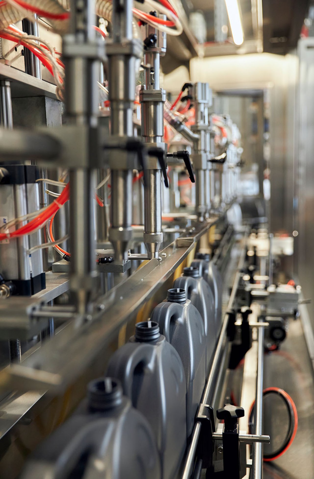 Produktionslinie mit grauen Kunststoffkanistern und Metallrohren in einer Fabrik.