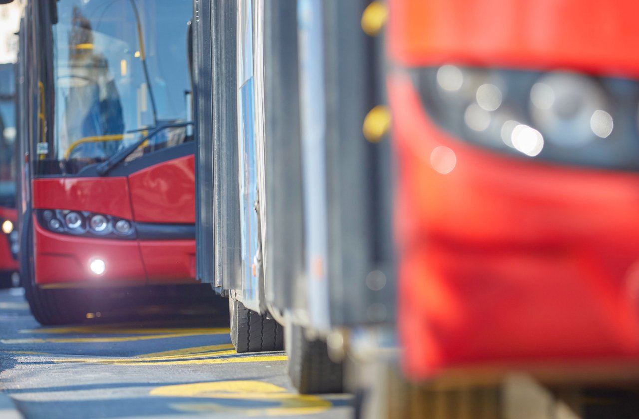 Rote LKW hintereinander auf einer Straße.