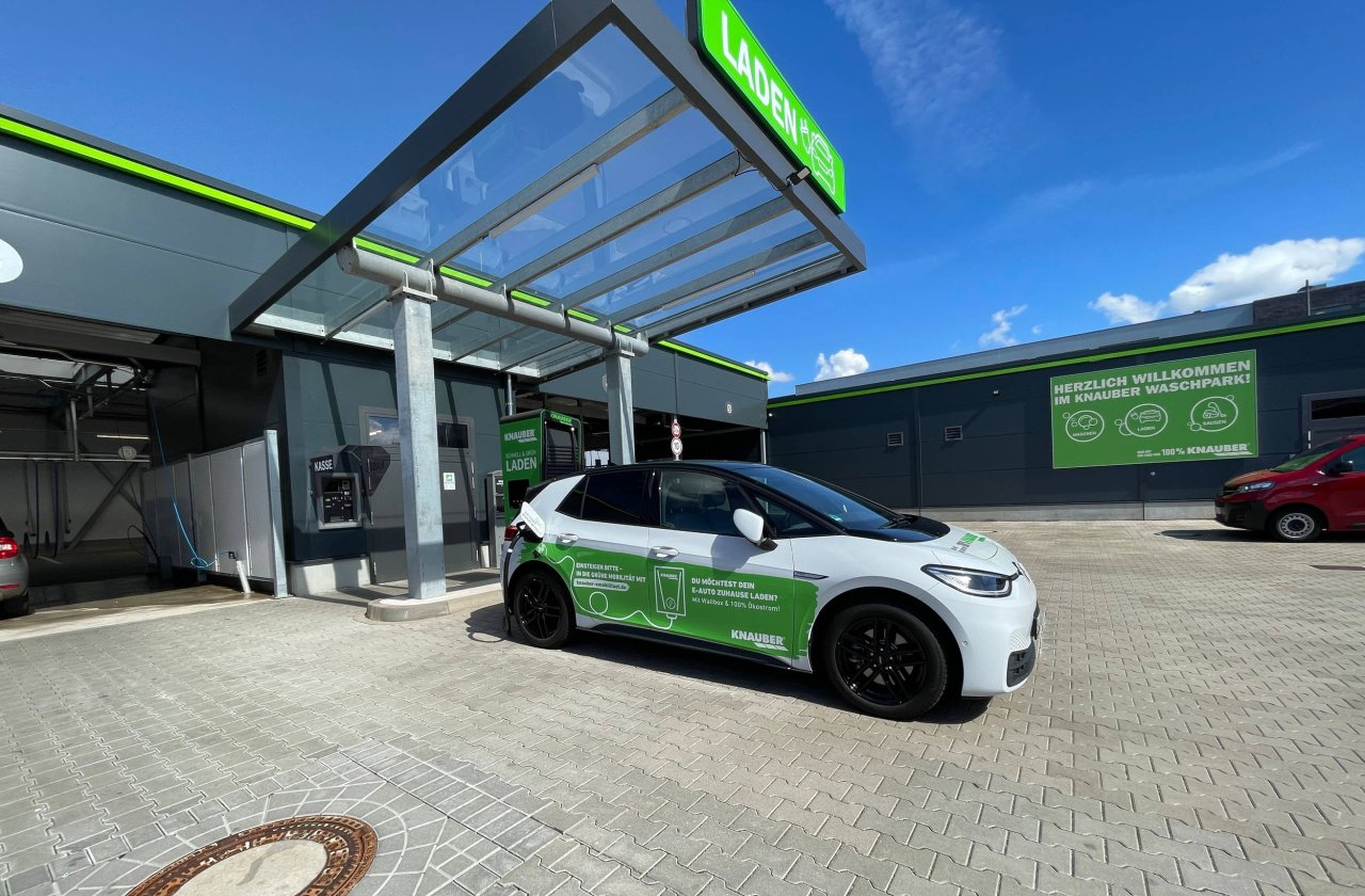 Ein weißes E-Auto steht vor einem Charger.